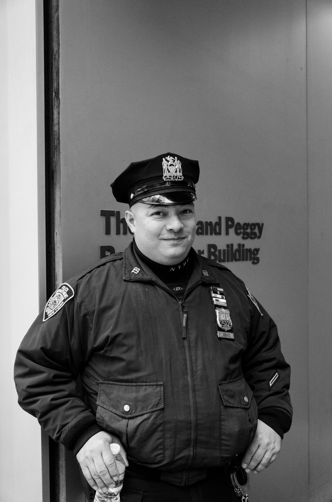 Grayscale photography of white police officer holding water bottle