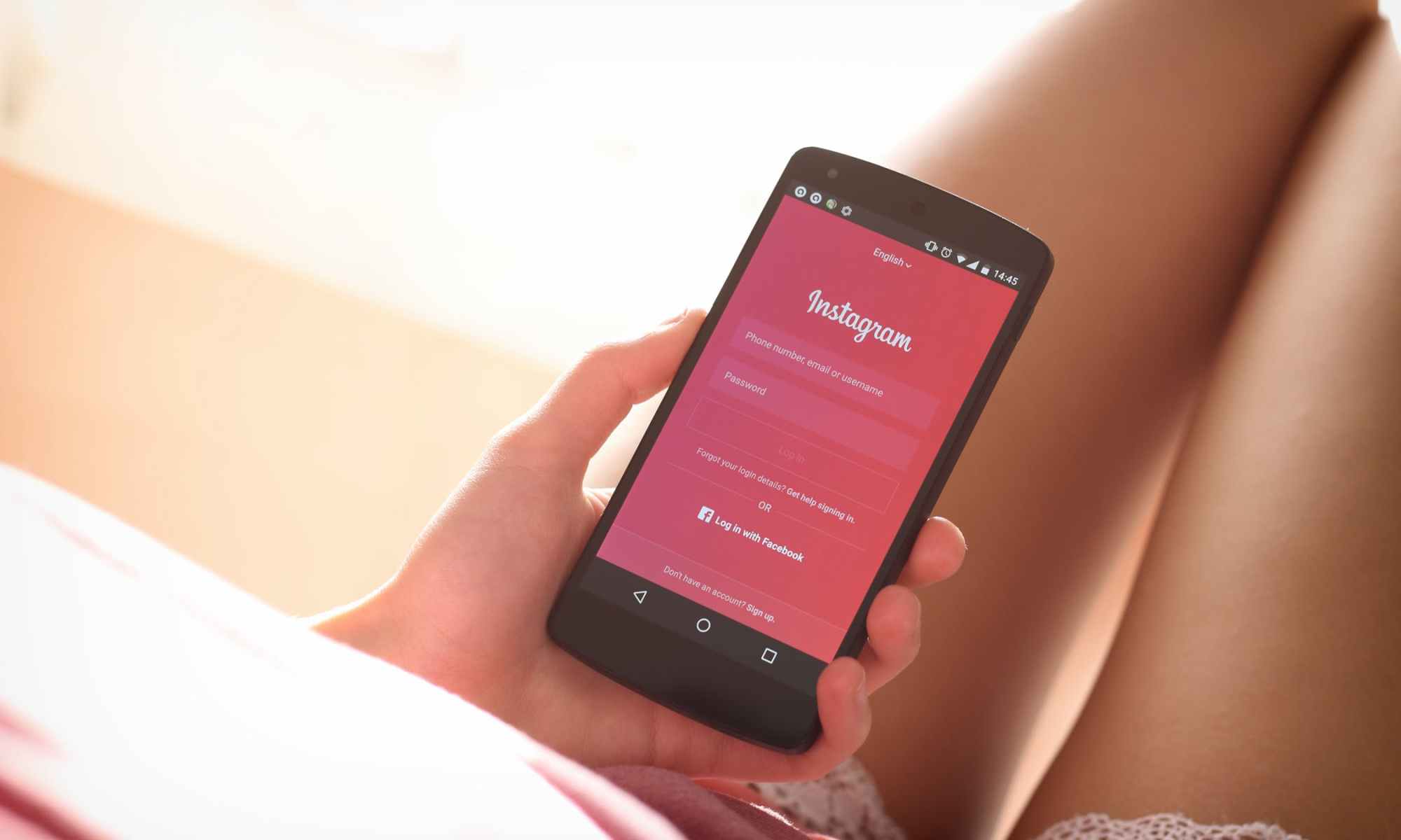 Woman with pink shorts and exposed legs holding phone with Instagram on