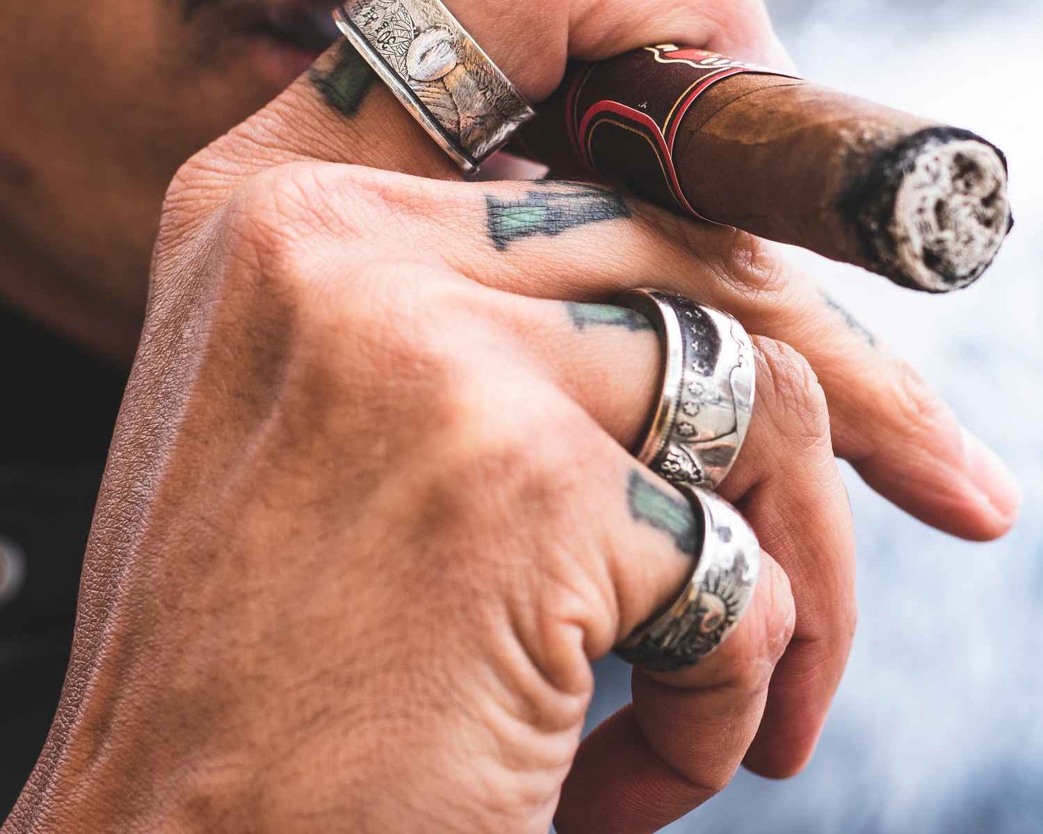 Gangster man with three silver rings smoking cigar