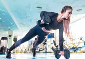 White woman dressed in black outfit working out with weights in gym